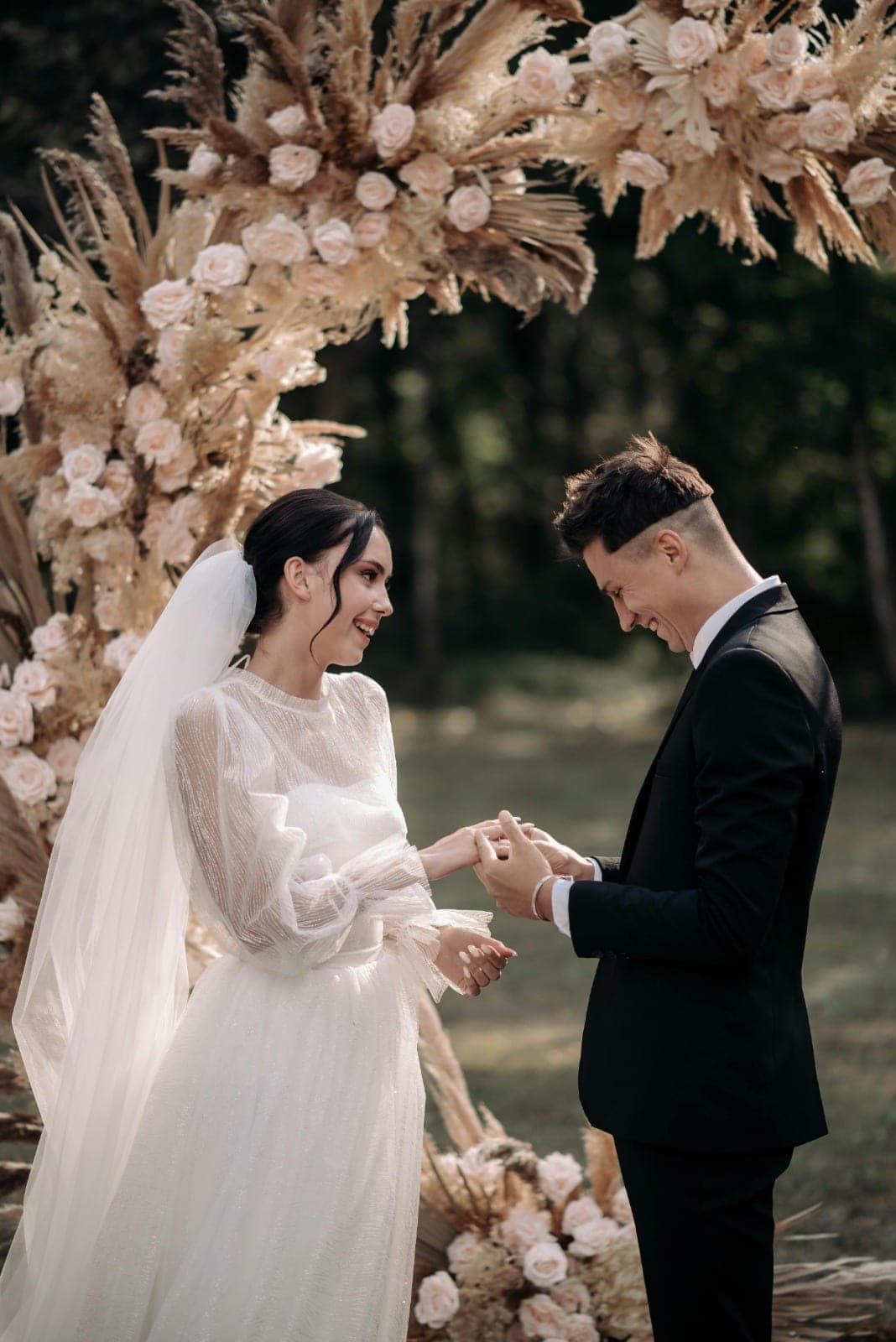 Exchanging rings beneath a floral ceremony arch