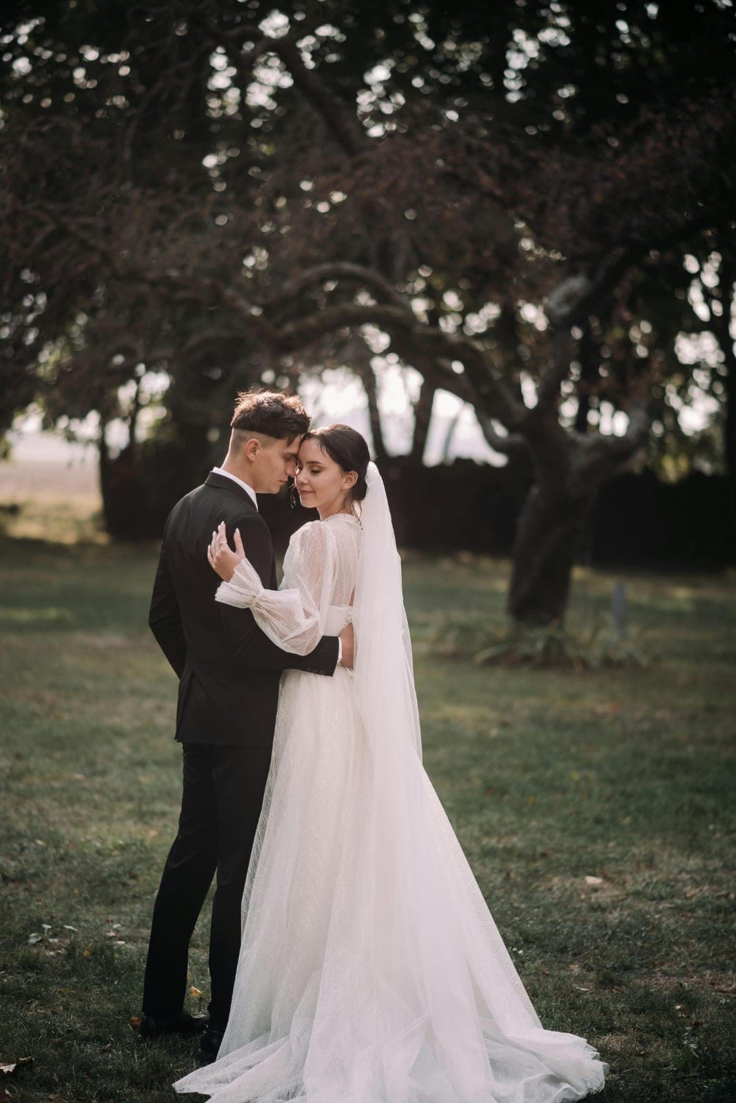 Bride and groom forehead to forehead among the trees