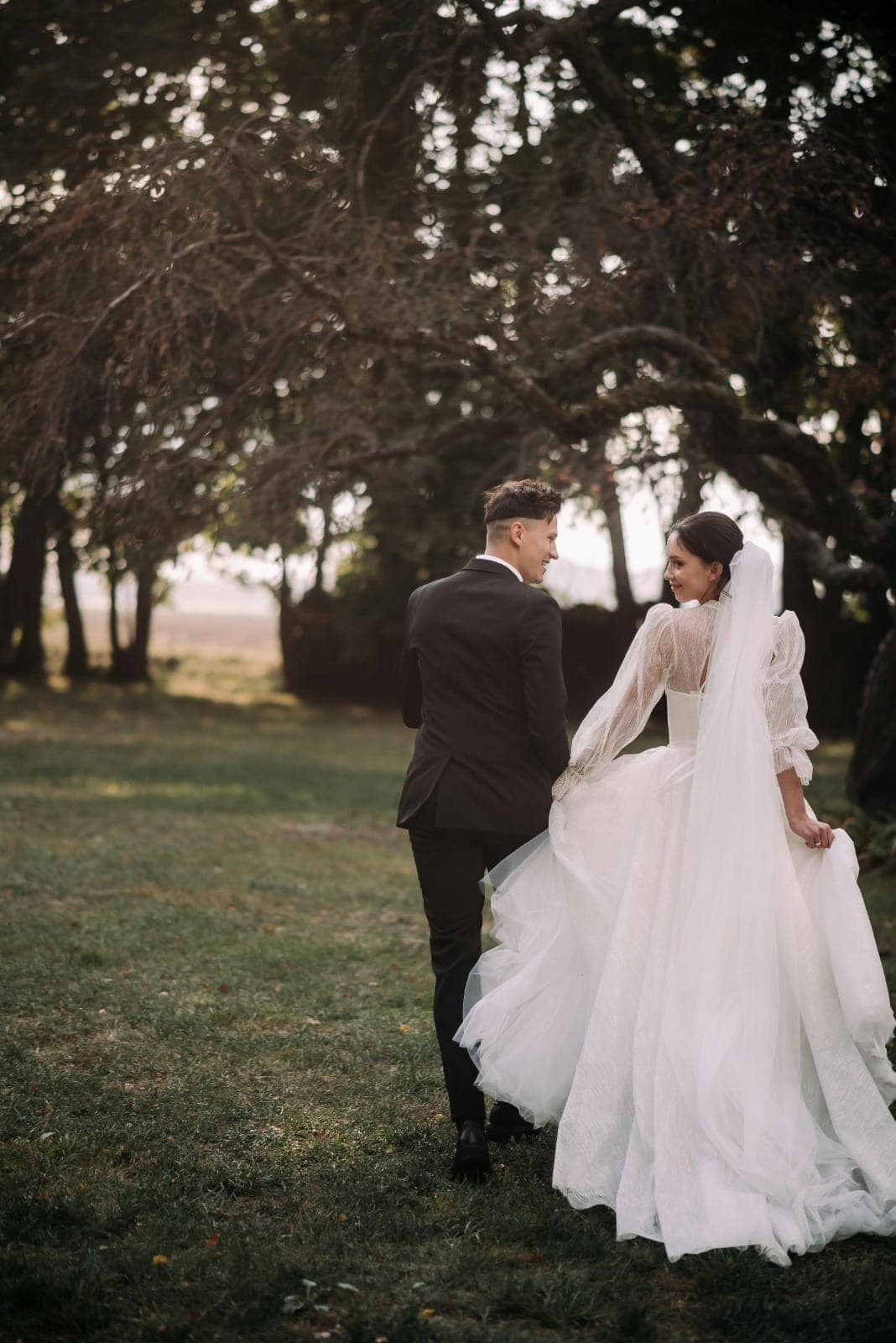 The couple walking through the trees, glancing back